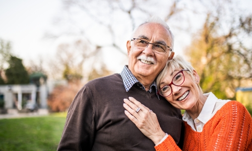 A retired couple hugging and smiling