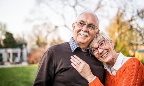 A retired couple hugging and smiling