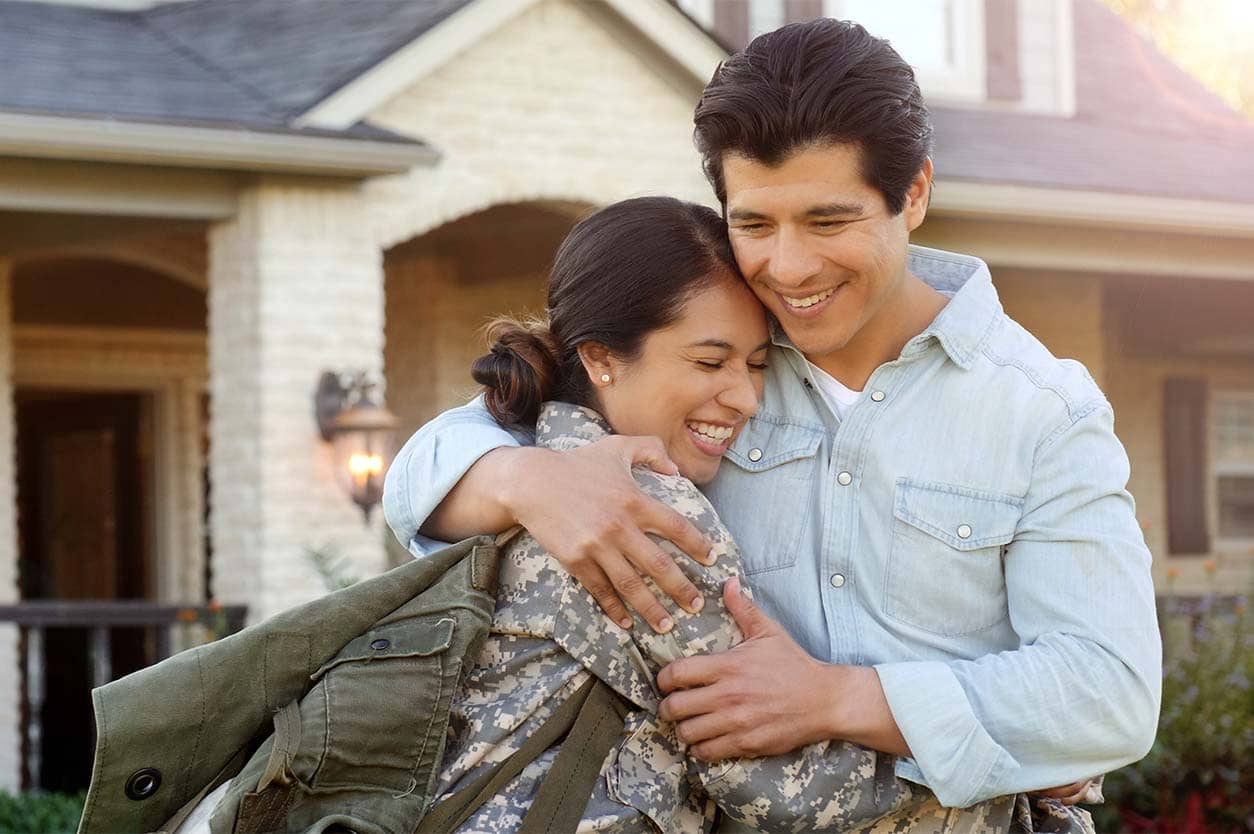 VA Loan A couple hugging in front of their home